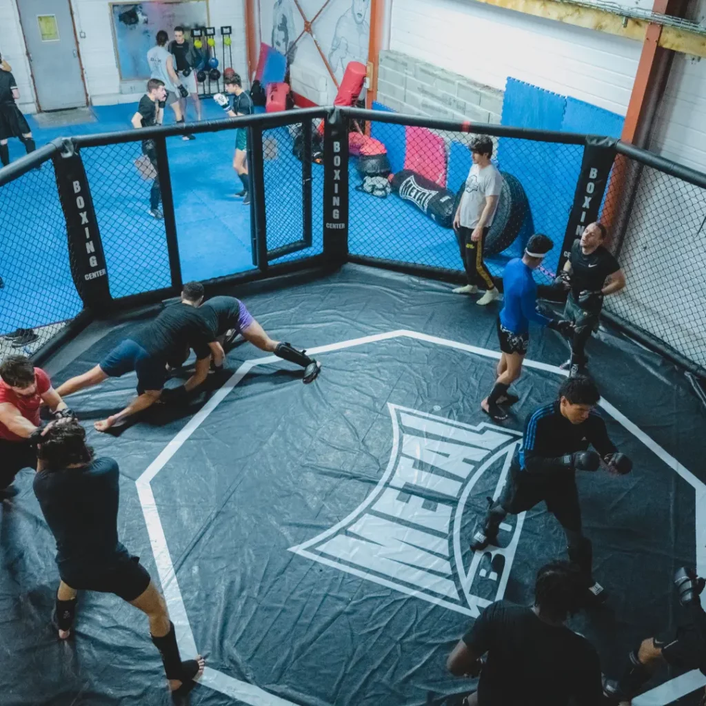 Groupe de personnes s'entraînant au MMA dans un ring de boxe spécialisé.